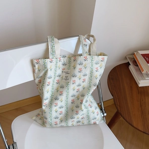 Dettaglio della borsa tote in cotone floreale con etichetta su una sedia bianca