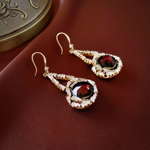 Vue détaillée de boucles d'oreilles rétro en or avec pierre rouge et zircons blancs