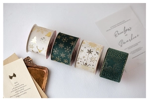 Detailed view of dark green and cream Christmas ribbons with gold foil holiday patterns