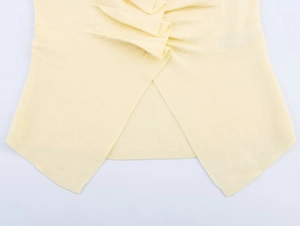 Close-up of cross-pleat detail on the hem of a yellow knit sweater top