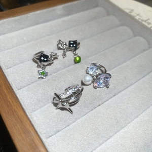 Detail view of sparkling star ear clips with black cat charms on gray velvet tray