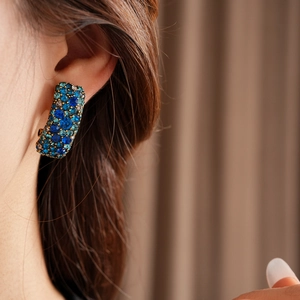 Gros plan de boucles d'oreilles bohèmes avec cristaux bleus et monture dorée