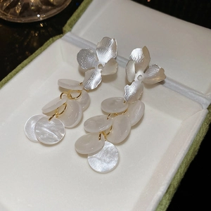 Close-up of floral silver studs with white pearlescent round discs and golden rings