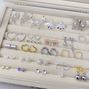 Detailed collection of zircon butterfly and pearl earrings displayed in a velvet jewelry box