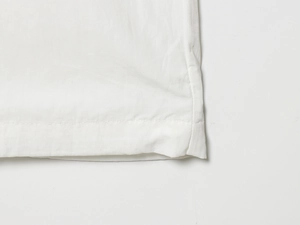 Détail de l'ourlet à double couture et de la texture du tissu blanc du pantalon