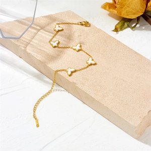 Detail of a gold butterfly bracelet with white shell inlays on a textured stone base