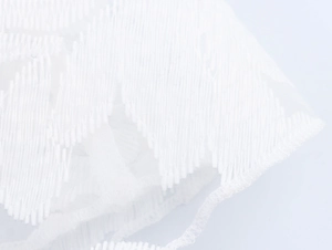 Macro detail of delicate white lace embroidery and fine mesh texture on dress