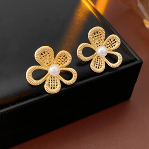 Gros plan de boucles d'oreilles fleur dorées avec perle sur une boîte à bijoux noire
