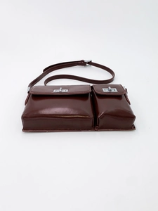 Detail of dark brown leather bag showing dual front pockets with silver twist-locks