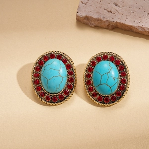 Macro view of vintage bohemian earrings with turquoise stone and red crystals on stone background