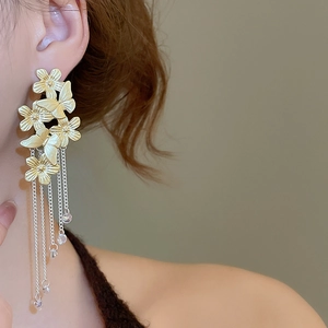 Detail of floral butterfly earrings with long metal tassel chains on a model