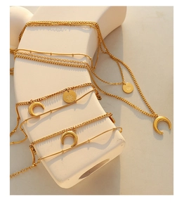 Detail of layered gold necklaces with crescent moon and star pendants on a ceramic stand