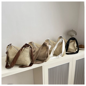 Detail view of woven straw tote bags in four colors with wide knot shoulder straps