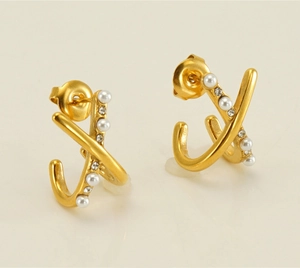 Close-up of golden X-shaped cross earrings with elegant pearls and small crystals