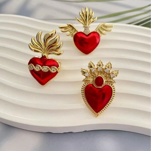 Adjustable gold heart wings ring with red enamel and zircon accents on a white stand