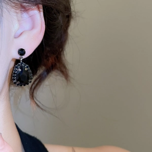 Close-up of model wearing elegant black teardrop earrings with crystals in retro style