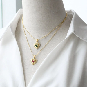 Double-layered gold heart necklace set with red and green zircon crystals on a model