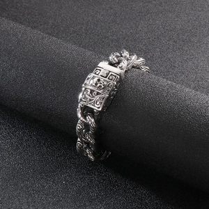 Gothic skull engraved stainless steel chain bracelet displayed on a dark cylindrical stand