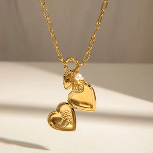 Golden heart locket necklace with pearl detail and small charm on a delicate chain