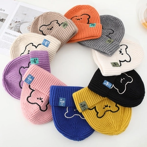 Top view of colorful knitted beanies with cute bear embroidery on white background