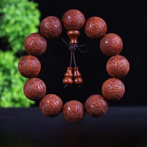 Dettaglio macro di grani di preghiera in sandalo con incisioni Buddha e mini zucche