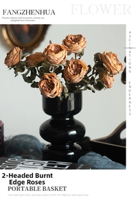 Detailed view of vintage orange burnt edge roses in a glossy black curved glass vase