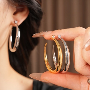 Detailed view of silver and gold C-shaped hoop earrings with zircon accents on a model