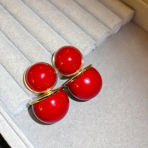Vue macro de boucles d'oreilles boules rouges double face avec base dorée sur velours
