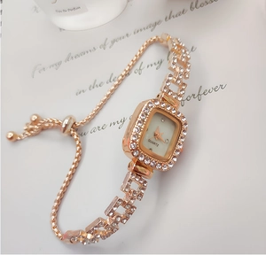 Detailed macro of rose gold square watch with crystal embellishments and adjustable chain