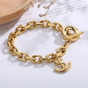 Close-up of gold chain bracelet featuring an OT buckle and nautical anchor pendant
