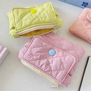 Flat lay of quilted diamond pattern coin purses in pink and yellow with button detail