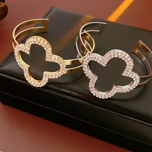 Dettaglio di bracciali a quadrifoglio in oro e argento con cristalli su pelle