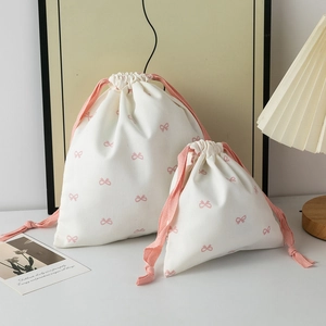 Close-up of cream drawstring storage bags with pink bow pattern in two sizes
