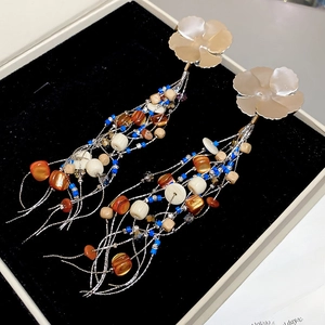 Macro shot of boho flower tassel earrings with shell beads in a black velvet jewelry box
