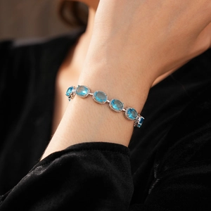 Detailed close-up of a silver bracelet featuring oval blue stones worn on a model wrist