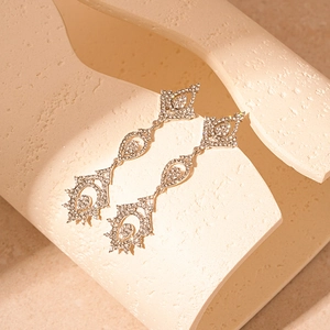 Détail de boucles d'oreilles pendantes en goutte avec strass sur présentoir artistique