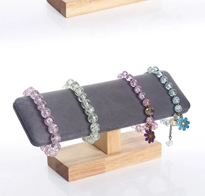 Detail of wooden jewelry stand with grey velvet bar displaying colorful beaded bracelets