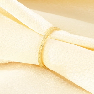 Detailaufnahme eines minimalistischen gold mattierten Edelstahlrings auf Seidenhintergrund