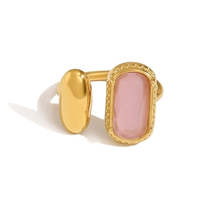 Détail d'une bague dorée réglable avec une gemme rose et un élément ovale en métal poli