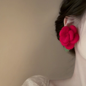 Close-up of elegant red flocked flower earring with a green leaf on female model