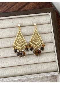 Macro detail of retro hollow triangle earrings with brown beads in a velvet tray