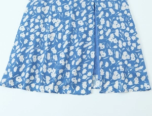 Détail de l'ourlet de la robe en mousseline bleue avec imprimé floral et fente sexy