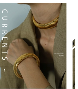 Close-up of chunky gold snake texture necklace and bracelet set on a model in green blazer