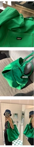 Macro detail of high-saturation green canvas tote bag showing UNSP label and outer pocket