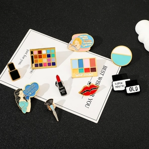 Detailed view of nine colorful makeup themed enamel pins on a decorative card display