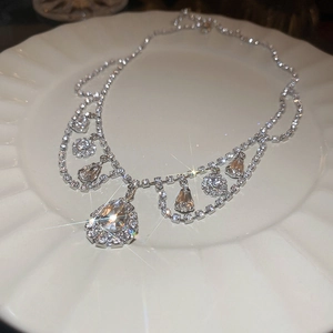 Macro shot of silver diamond choker with teardrop pendants on a white ceramic plate