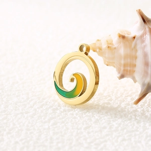 Makro-Detail eines 18k Gold-Wellenanhängers mit grünem Emaille und Muschel-Akzent