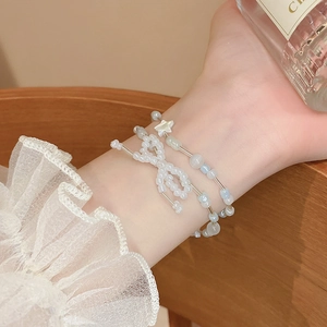 Detail of sweet double-layer beaded bracelet with bow and star charms on wrist