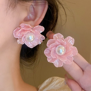 Delicate pink floral earrings with a white pearl center shown on an Asian model's ear