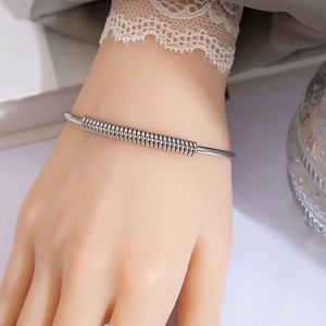 Detail shot of a silver metal knot bracelet with spiral spring design on a model wrist